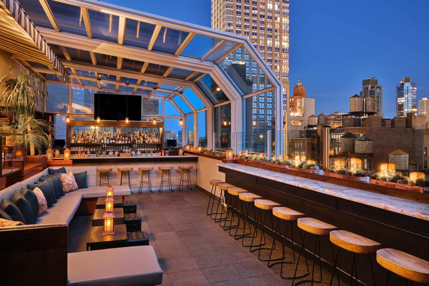 Rooftop bar with views of lights shining in New York city at dusk