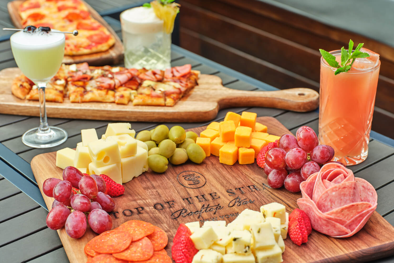 Top of the Strand charcuterie boards with meats, cheeses, and light snacks surrounded by various cocktails